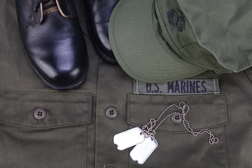 U.S. MARINES cap, dog tags and boots on olive green uniform background