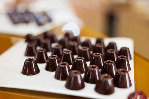 Dark chocolate truffles in thimble shape, served on white tray