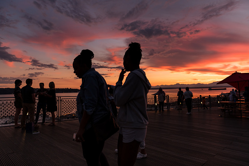 Seattle, USA - Aug 23, 2022: People enjoying a brilliant sunset over Elliott bay from Pike Place Market.