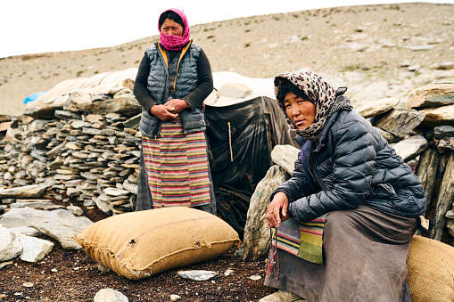 Leh, India, August 15th, 2022: Local women resting during a break while transporting heavy sacks on the mountains