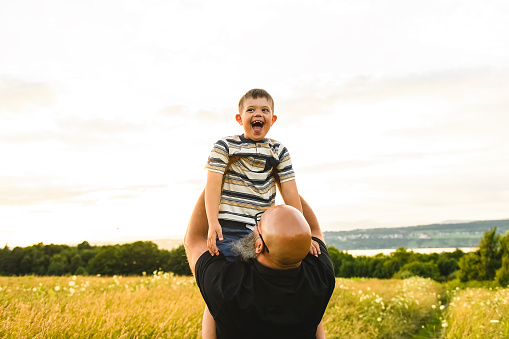 A Portrait of a little boy with down syndrome in sunset on summer season with his father