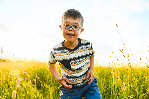 A Portrait of a little boy with down syndrome in sunset on summer season