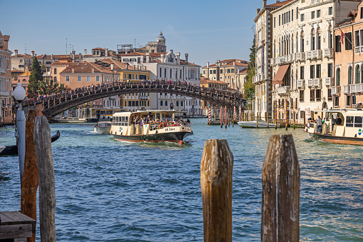 Venice, Italy - October 8th 2022:  A water bus, a vaporetto under a wooden bridge over Canale Grande in the center of the old and famous Italian city Venice