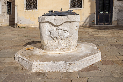 Venice, Italy - October 9th 2022:  Old well made of marble on a small public square in the center of the old and famous Italian city Venice