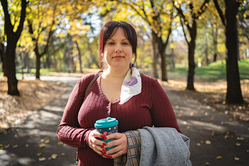 Portrait of body positive young Caucasian woman, at the public park during autumn day