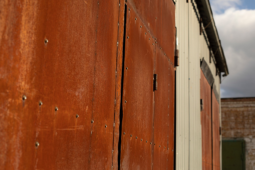 Rusty gates in industrial area. Warehouse details. Steel gates. Rust on metal.
