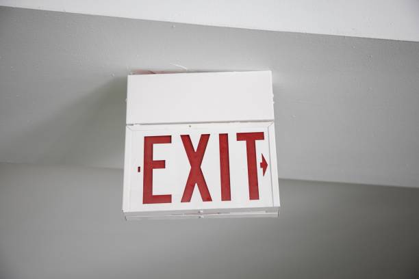 istock Red and white Exit sign hanging from the ceiling under the lights 1438937977