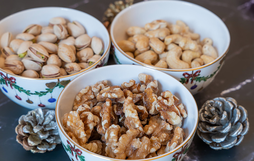Three bowls of Christmas godies on the table. Pistachio, walnuts and cashwe nuts in Christmas bowls.