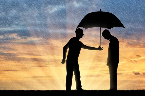 Concept of Altruism in society Altruist man shares an umbrella with another sad man standing in the rain. Concept of Altruism in society altruism stock pictures, royalty-free photos & images