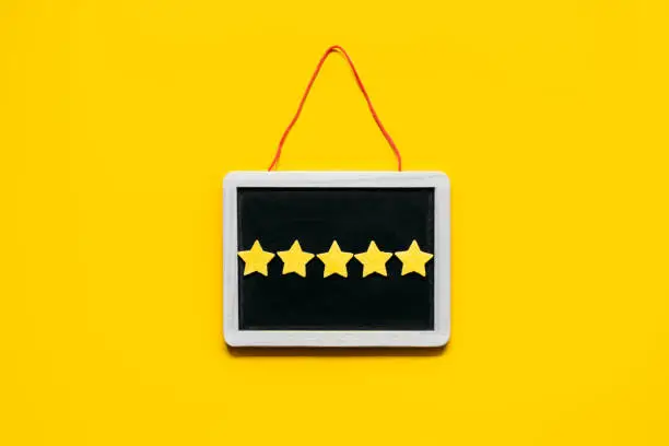 Photo of Customer Experience, Review Concept. Five yellow stars excellent rating in frame on yellow background. Customers Ratings and Reviews