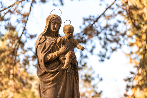 historic stone statue of holy mary with little jesus in sunshine