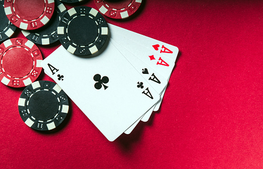 A poker game with a four of a kind or quads hand. Chips and cards on the red table