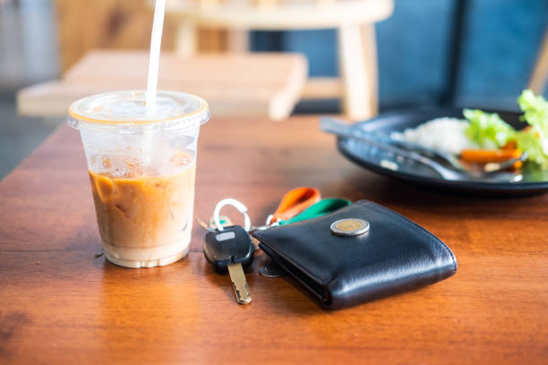 Ice coffee in plastic glass with wallet in cafe Ice coffee in plastic glass with wallet and car keys on wood table in cafe phone wallet keys stock pictures, royalty-free photos & images