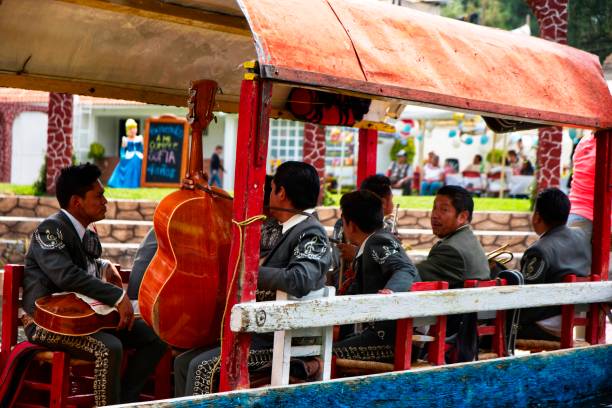 Mariachis in a trajinera boat in Xochimilco, Mexico City Mexico City, Mexico – April 28, 2019: Mariachis in a trajinera boat in Xochimilco, Mexico City singing around the canal to all people wearing typical clothes. trajinera stock pictures, royalty-free photos & images