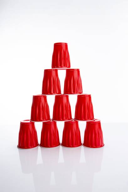 istock Vertical of a cup pyramid made of red disposable plastic cups against a white background 1438951846
