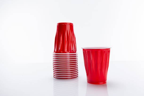 istock Red disposable plastic cup put next to a horizontal stack of cups against a white background 1438952463