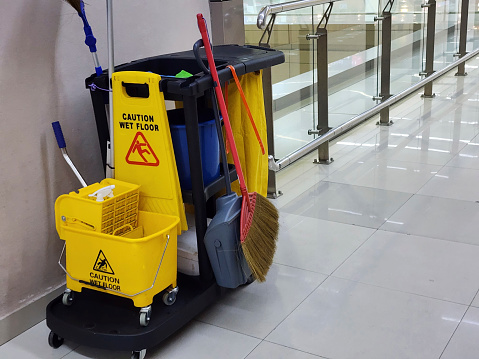 Janitorial and mop bucket on cleaning in process with copy space indoor.