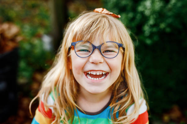 Fall portrait of little preschool girl in autumn park on warm october day with oak and maple leaf. Child with lot of leaves. Family outdoor fun in fall. Kid smiling. Healthy funny child with glasses Fall portrait of little preschool girl in autumn park on warm October day with oak and maple leaf. Child with lot of leaves. Family outdoor fun in fall. Kid smiling. Healthy funny child with glasses. children laughing stock pictures, royalty-free photos & images