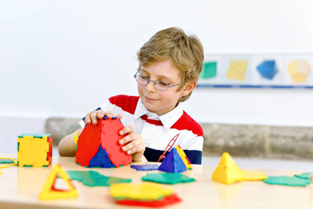 istock Happy kid boy with glasses having fun with building and creating geometric figures, learning mathematics and geometry 1438963970