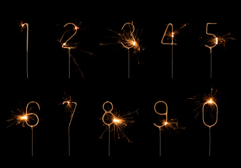 Golden sparklers in numbers digits shape set, burning bright with sparks, isolated on black background