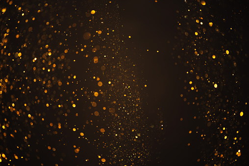 Warm glowing golden glitter festive lights abstract bokeh dark texture background