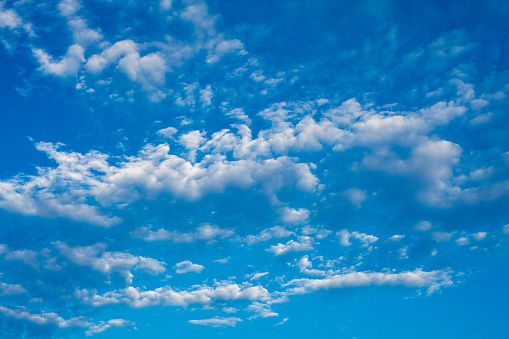 Small white clouds in clear blue sky background