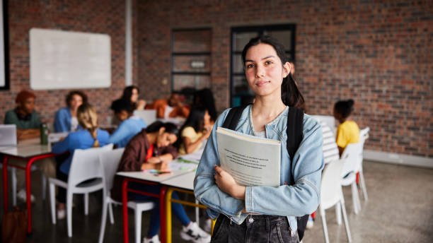 istock Confident young female college student with books standing in a classroom 1438965090