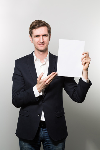 A vertical shot of a well-dressed male pointing to a blank paper
