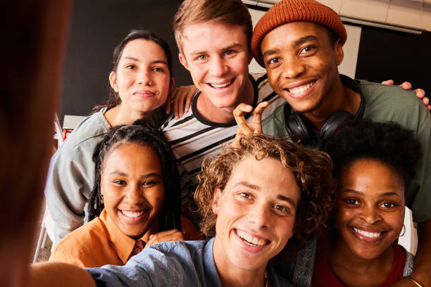 istock Smiling young college students taking selfies in a classroom 1438967952