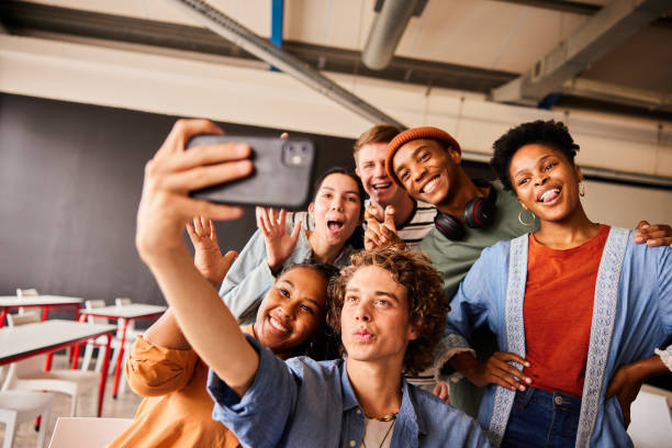 istock Young college students making faces and taking selfies in a classroom 1438968729