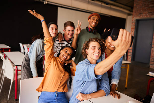 istock Young college students making face and taking selfies in a classroom 1438969154