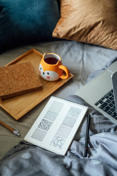 istock Doodling for Beginners, How To start Doodle. Doodle simple drawings sketch in notebook near laptop and tea coffee cup at bad in home. 1438969205