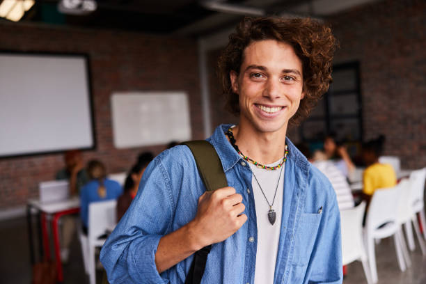 istock Young male college student smiling in a class with students in the background 1438969247