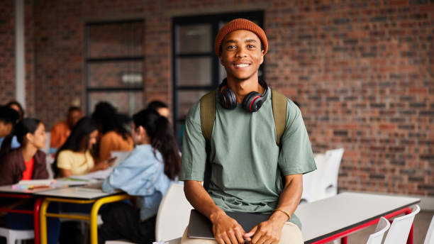 istock Smiling young male college student standing in a classroom 1438971468