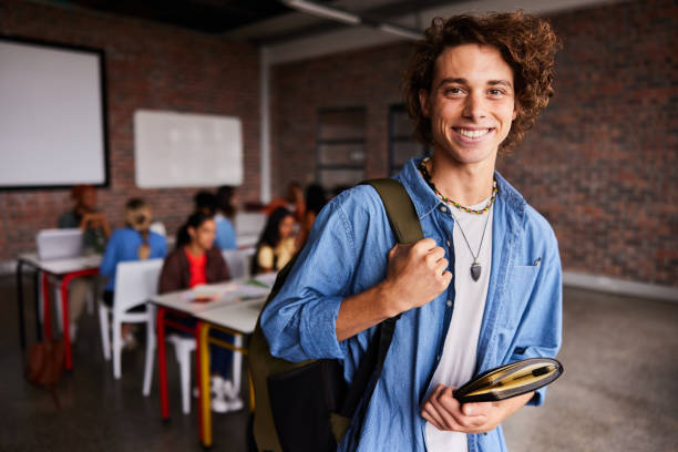 istock Smiling young male college student standing in a classroom 1438971921