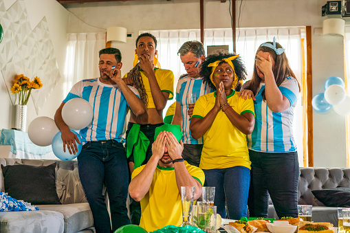Group of people of different ages and ethnicities from the teams of Brazil and Argentina are watching the matches of the soccer world cup