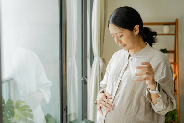 asiatische schöne schwangerschaftsfrau trinken ein glas milch für die gesundheitsversorgung. - freshness human hand mother family stock-fotos und bilder