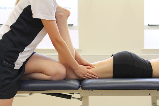 Massage physical therapist providing a patient with a thigh and hamstring massage