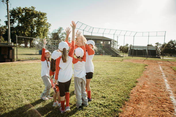 Team of little league baseball players huddle on field during practice or game stock photo