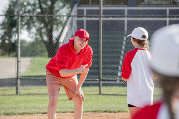 el entrenador le da instrucciones a la jugadora de béisbol de las ligas menores mientras está lista para batear durante el juego - baseball bat baseball little league baseballs fotografías e imágenes de stock