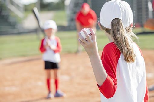 Little girl pitches during little league baseball game