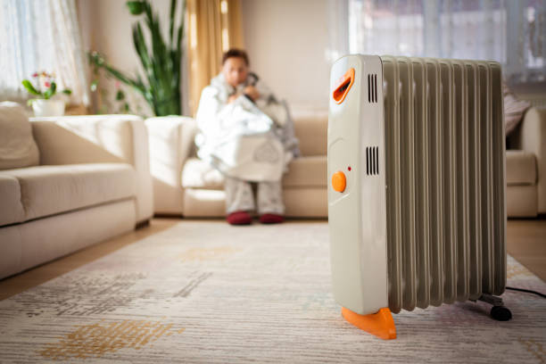 istock woman warming her hands over electric heater at home 1438976073