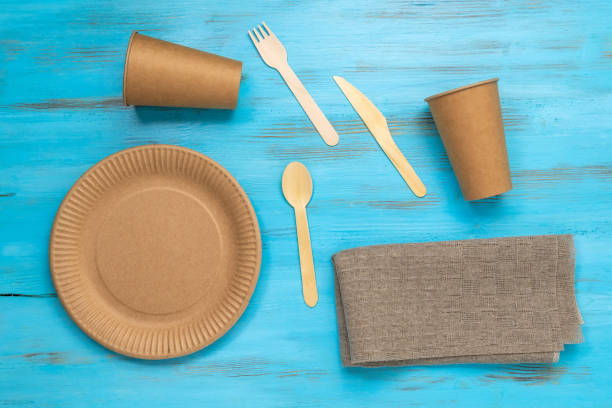 istock Eco friendly from paper and wooden cutlery on light table. Plastic tree. Top view. Copy space 1438977526