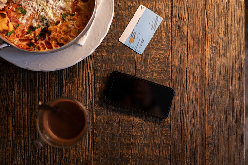 Above view of a credit card, smart phone, food plate and a glass of hot chocolate on a table, still life, no people