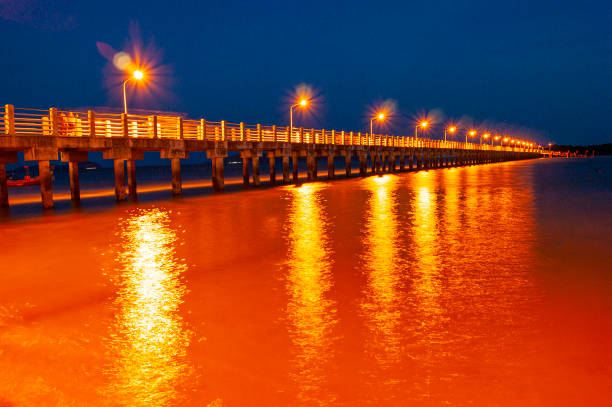 Pier at night with yellow lights on a background of blue sky stock photo