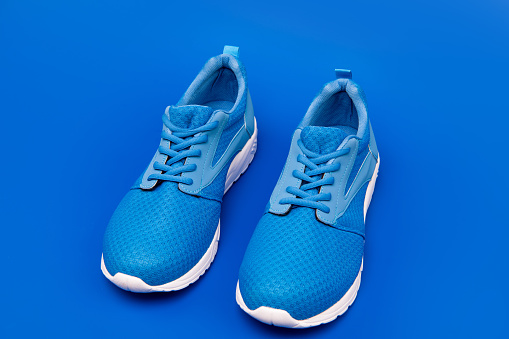 athletic footgear for running. pair of comfortable sport shoes. sporty blue sneakers. shoes on blue background. shoe store. shopping concept. footwear for training.