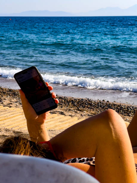 istock Sunbathing woman looking at mobile phone. 1438983670