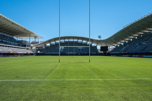 Professional soccer stadium with tribunes, illumination, green grass and cloudy blue sky