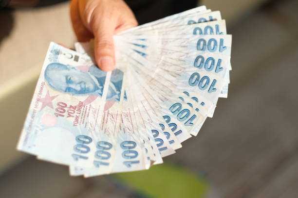 istock Hand holding Turkish Lira in front of white background 1438987553