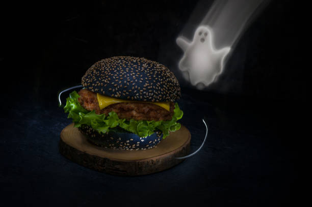 暗い背景にハロウィーンの黒いハンバーガーの接写。パーティーのためのハロウィーンの食べ物のアイデア - photography close up side view halloween ストックフォトと画像